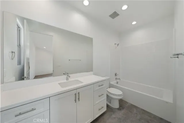 a bathroom with a toilet a sink a mirror a bathtub and vanity