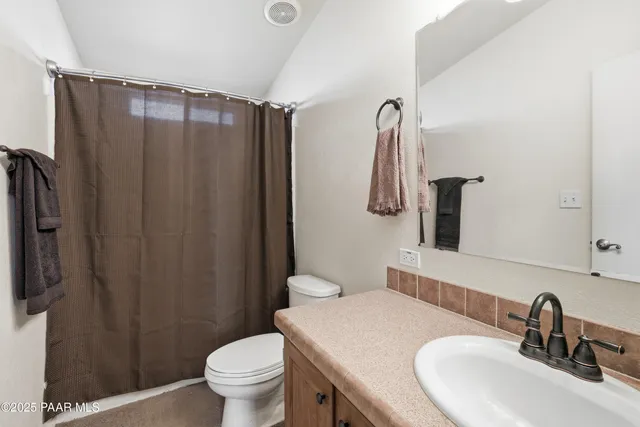 a bathroom with a sink a toilet and shower curtain