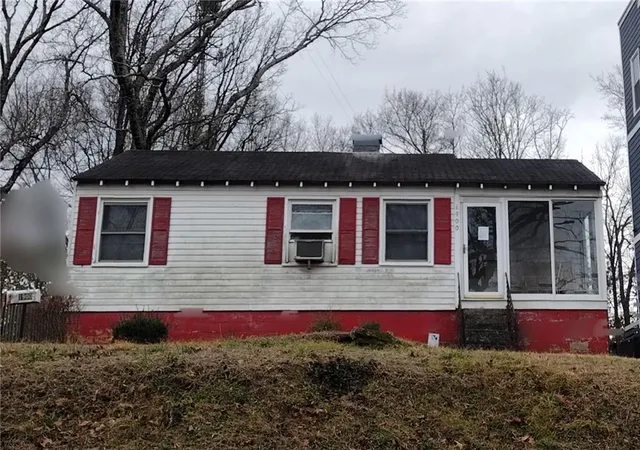a view of a house with a small yard and a large tree