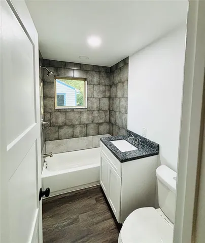 a bathroom with a granite countertop toilet sink and mirror