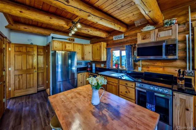 a kitchen with stainless steel appliances granite countertop a sink a stove top oven a chimney and a refrigerator