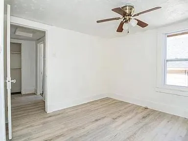a view of empty room with wooden floor and fan