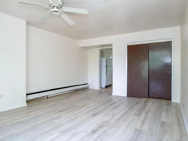 an empty room with wooden floor closet and fan