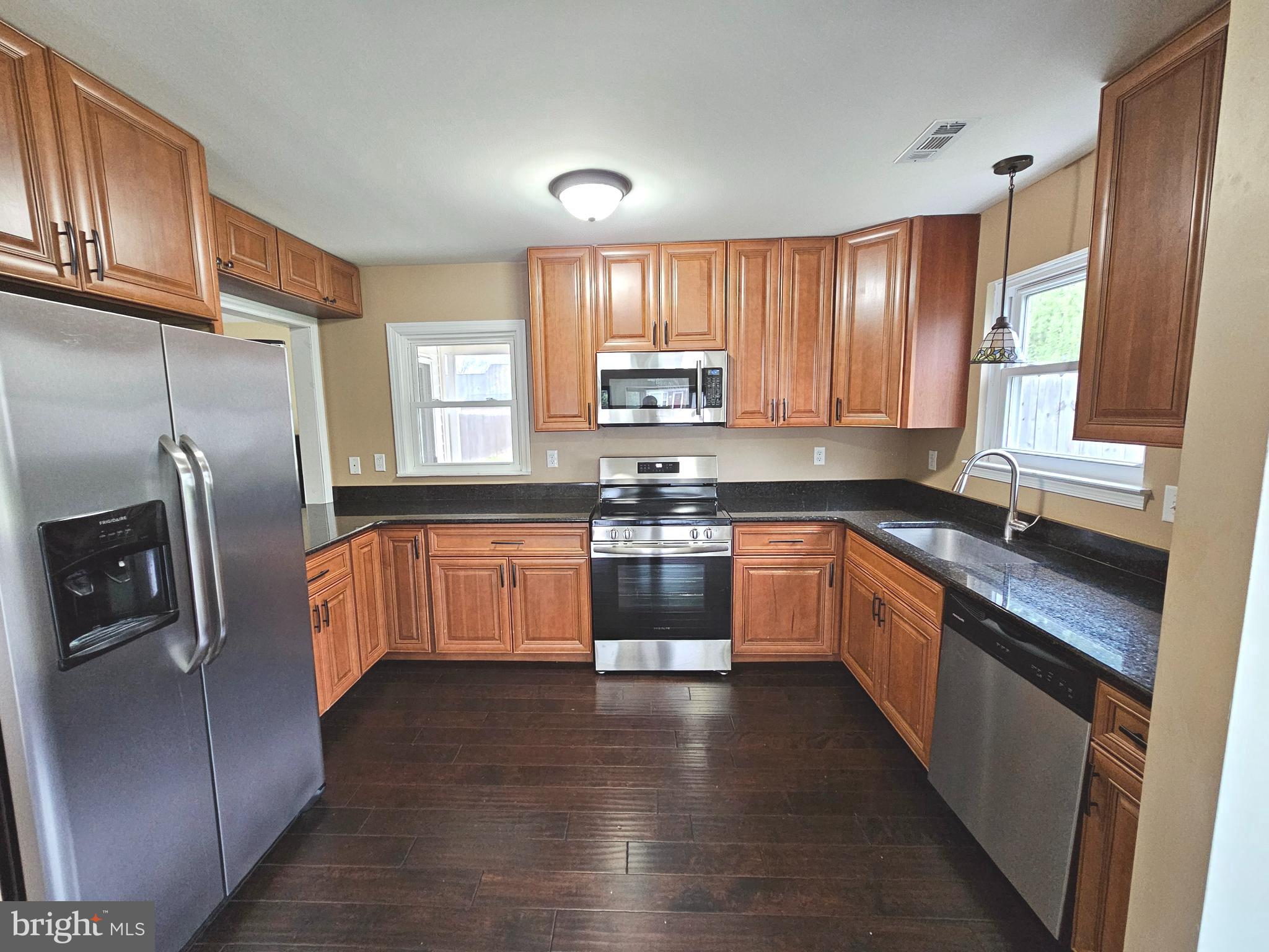 7 Gristmill Drive Dover, DE 19904 - Photo 8 of 26 a kitchen with granite countertop a refrigerator and wooden cabinets