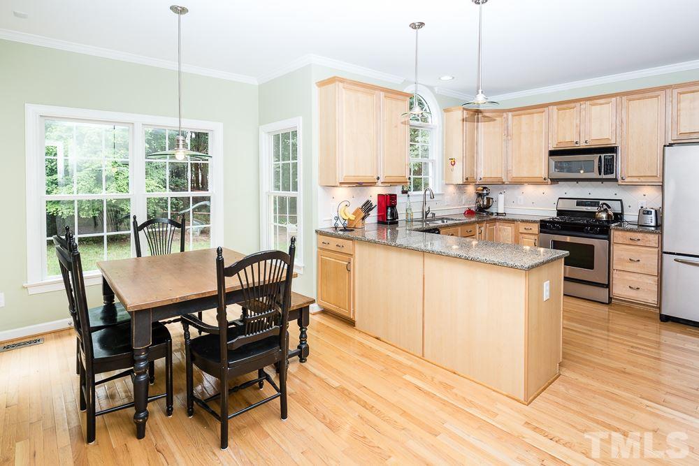 5016 Big Creek Road Raleigh, NC 27613 - Photo 4 of 25 a kitchen with stainless steel appliances granite countertop a stove top oven a refrigerator a sink and chairs