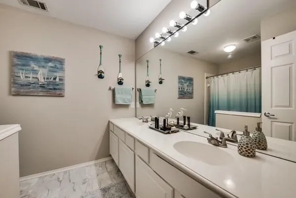 a bathroom with double vanity and a mirror