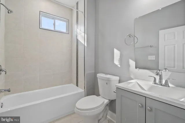 a bathroom with a toilet a sink a mirror a bathtub and vanity