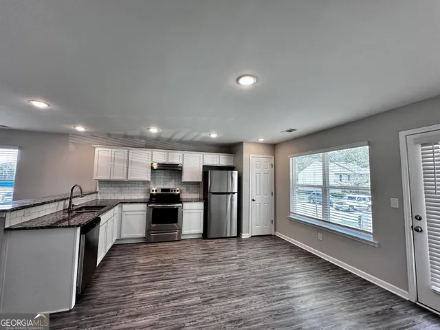 an open kitchen with kitchen island granite countertop a stove top oven a sink and dishwasher with wooden floor