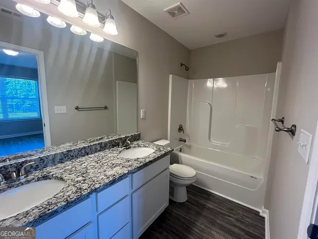 a bathroom with a granite countertop sink toilet and shower