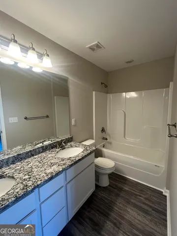 a bathroom with a granite countertop sink mirror vanity and toilet