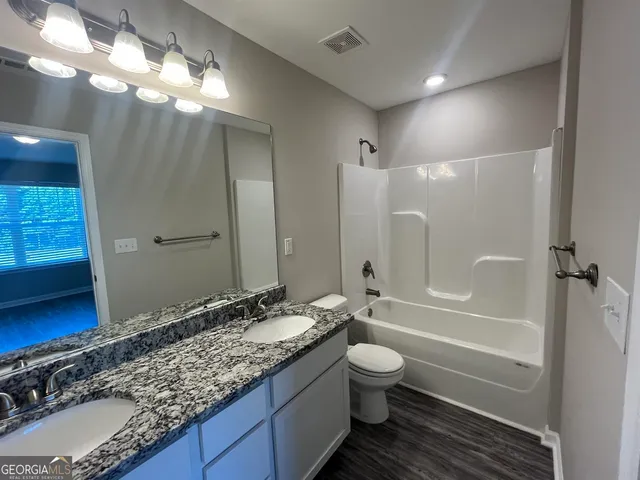 a bathroom with a granite countertop sink a toilet and bathtub