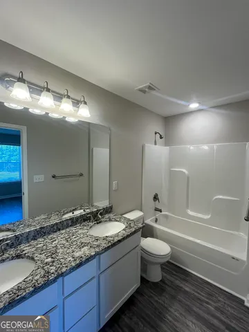 a bathroom with a granite countertop sink a toilet and a bathtub