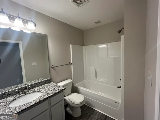 a bathroom with a granite countertop sink toilet and shower