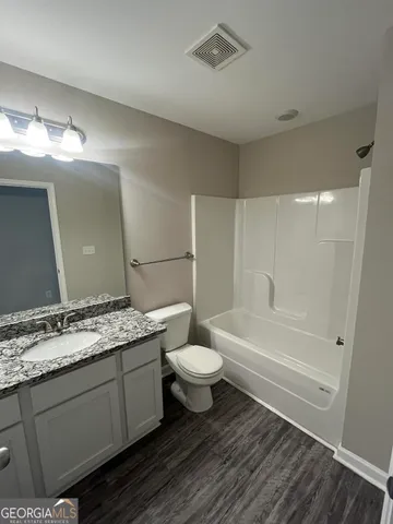 a bathroom with a granite countertop sink toilet a large mirror a bathtub and shower