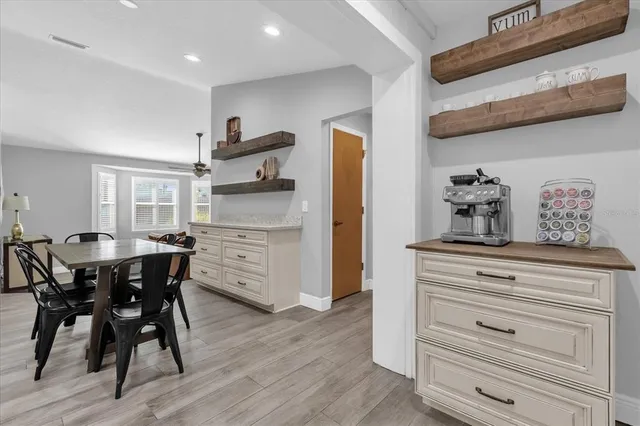 a kitchen with stainless steel appliances granite countertop a table chairs in it and wooden floors