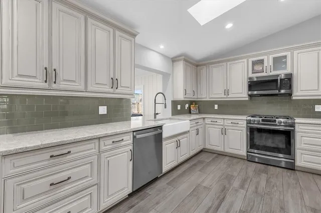 a kitchen with granite countertop white cabinets and stainless steel appliances