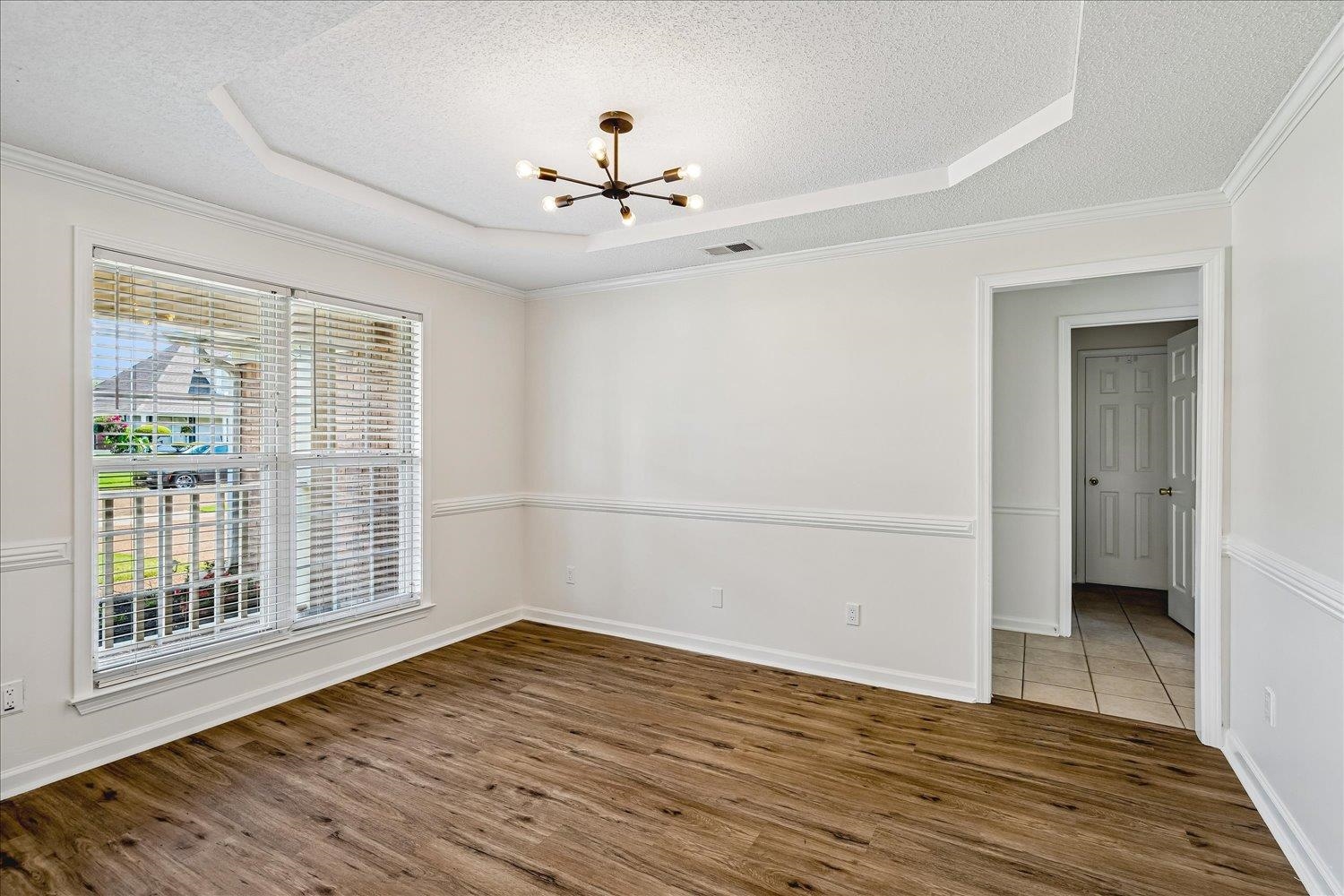 6335 Needle Ridge Road Bartlett, TN 38135 - Photo 6 of 25 Spacious room featuring wood-finish flooring, a tray ceiling with a modern light fixture, and a large window with blinds