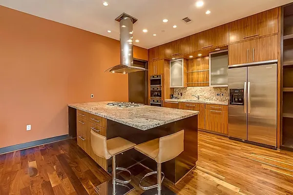 a kitchen with kitchen island a counter top space a sink stainless steel appliances and cabinets