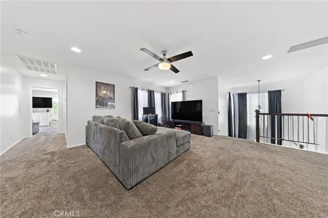 a living room with furniture a ceiling fan and a flat screen tv