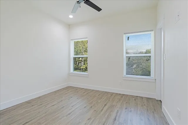 an empty room with wooden floor and windows