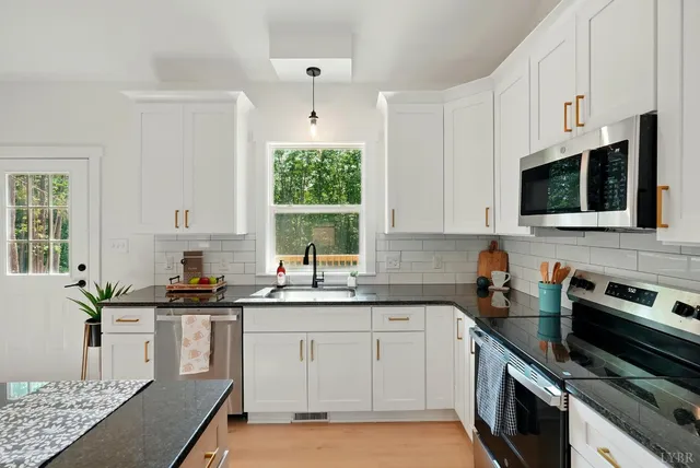 a kitchen with granite countertop a sink window and cabinets