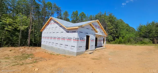 a view of a wooden house with a yard covered with snow in the background