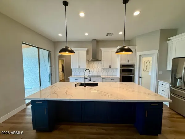 a kitchen with kitchen island a sink stainless steel appliances and wooden floor