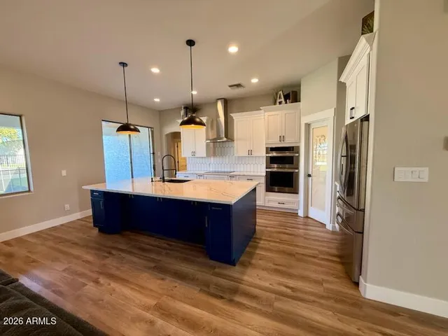 a large kitchen with stainless steel appliances kitchen island granite countertop a large counter top and wooden floors