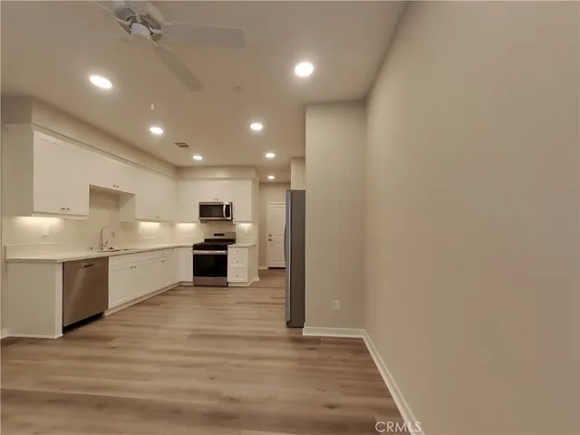a open kitchen with a sink and dishwasher a stove top oven with wooden floor