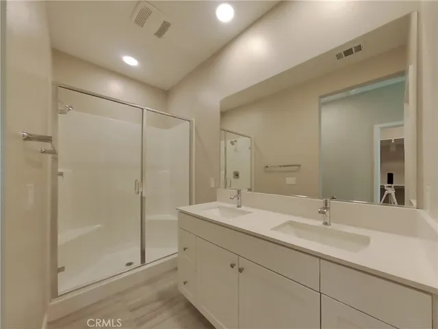 a bathroom with double sink shower and two mirror