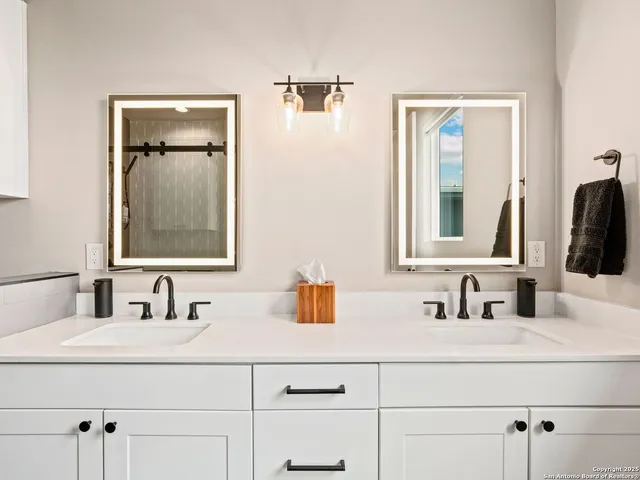 a bathroom with double vanity sink and two mirror
