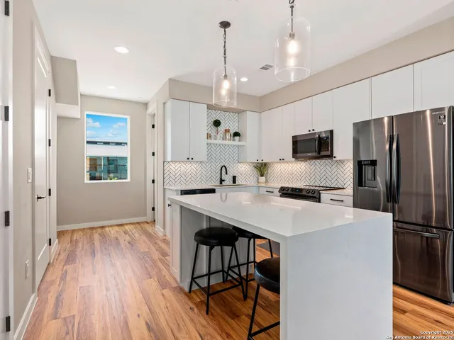a kitchen with kitchen island white cabinets and stainless steel appliances