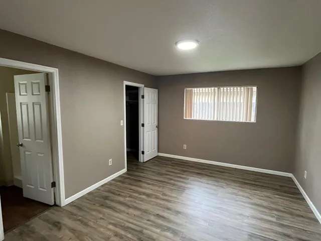 an empty room with wooden floor and windows
