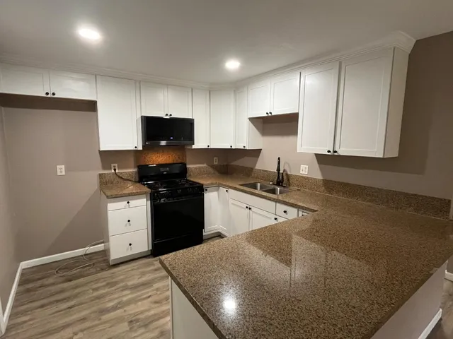 a kitchen with granite countertop a stove a sink and a refrigerator
