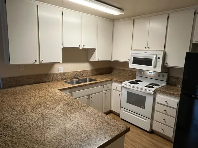 a kitchen with granite countertop a stove a sink and a microwave