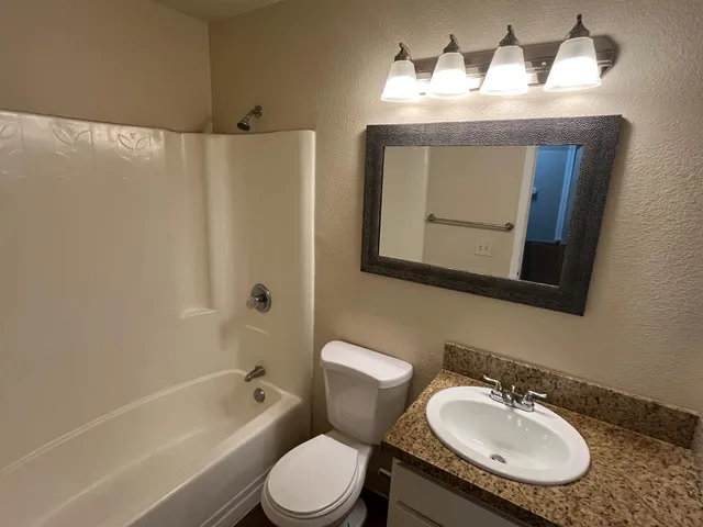 a bathroom with a granite countertop toilet sink and mirror
