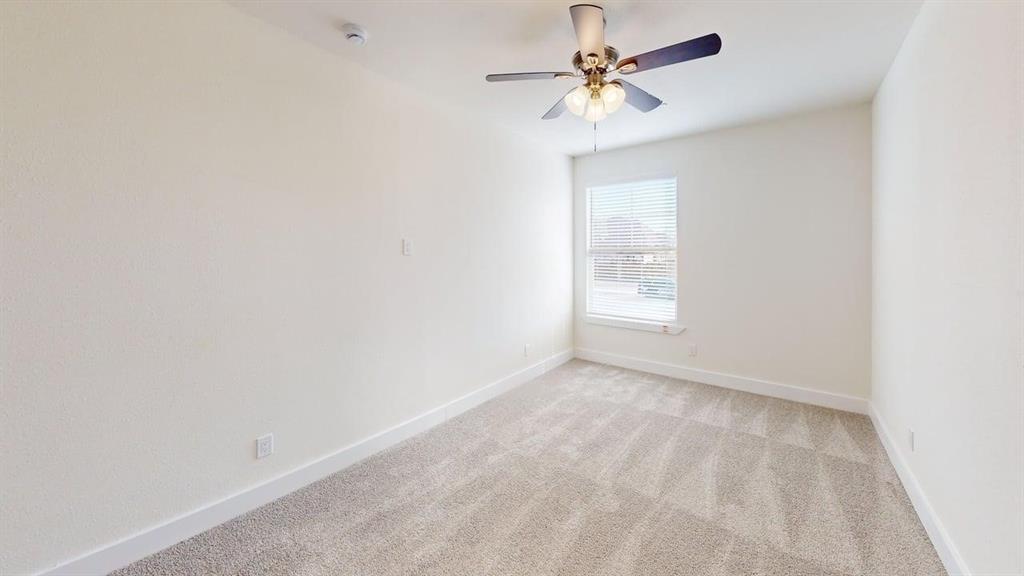 353 Buck Ridge Drive Little Elm, TX 75068 - Photo 15 of 23 Empty room with a ceiling fan and light colored carpet