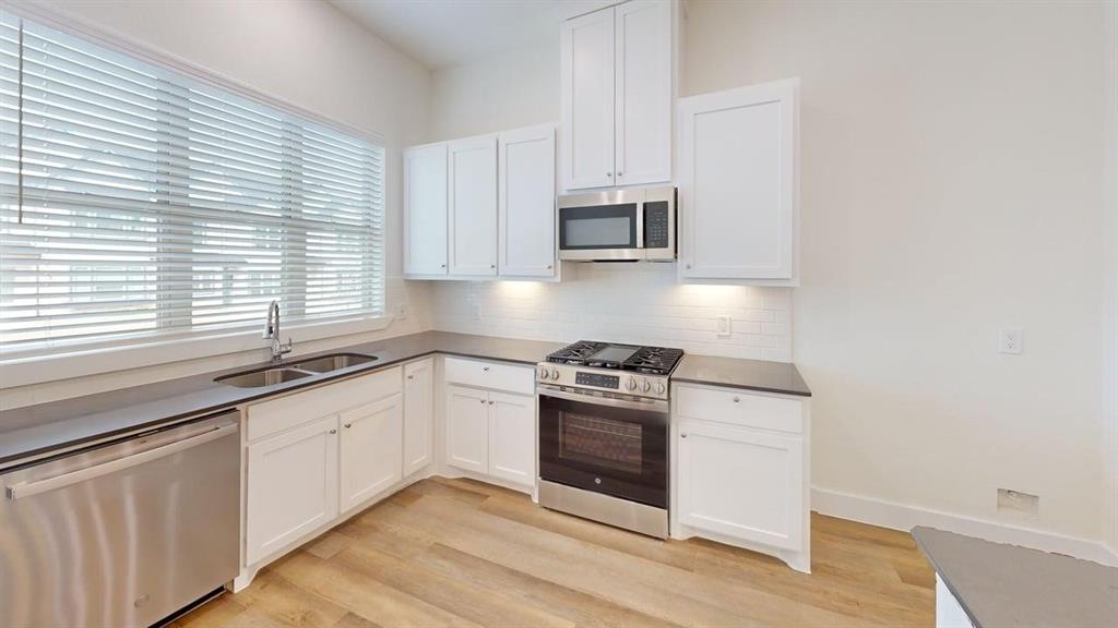 353 Buck Ridge Drive Little Elm, TX 75068 - Photo 4 of 23 Kitchen featuring stainless steel appliances, white cabinetry, and light wood finished floors