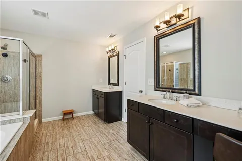 a spacious bathroom with a double vanity sink a mirror and a shower