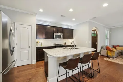 a kitchen with stainless steel appliances kitchen island granite countertop a refrigerator a stove top oven a sink with island and chairs