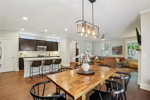 a dining room with wooden floor a chandelier a wooden table and chairs