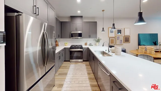 a kitchen with stainless steel appliances a refrigerator sink and wooden floor