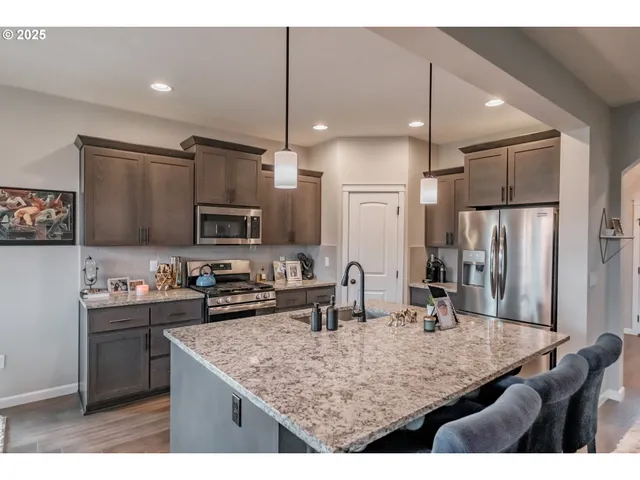 a kitchen with stainless steel appliances kitchen island granite countertop a table chairs in it and wooden floors