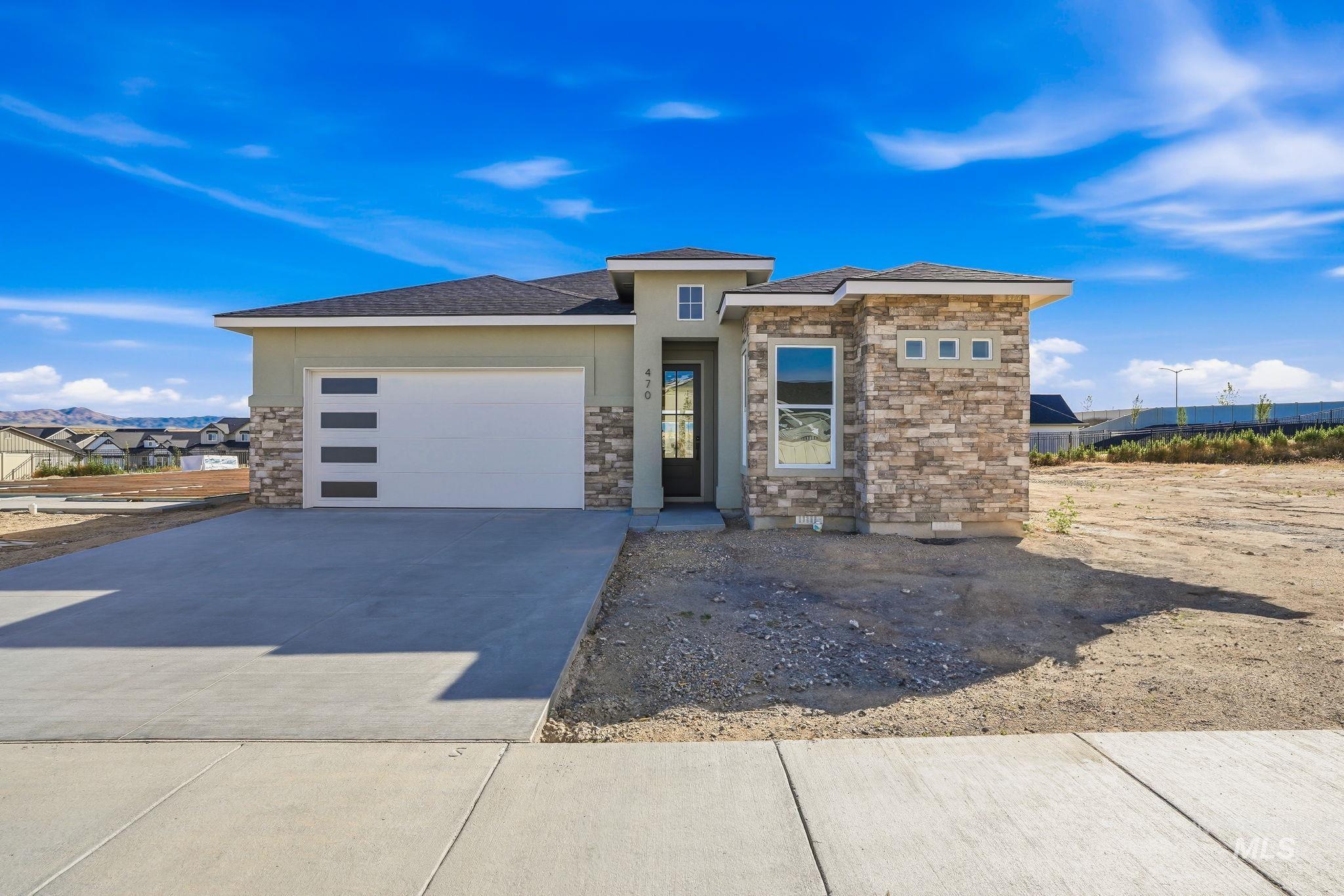 Contemporary stucco exterior featuring stone accents, a modern garage door with frosted glass panels, an asphalt shingle roof, and a concrete driveway with an integrated sidewalk