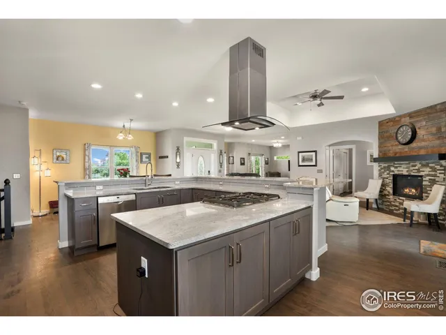 a kitchen with stainless steel appliances granite countertop a sink a stove and a wooden floors
