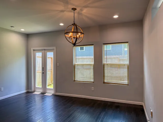 a view of an empty room with wooden floor and window