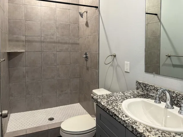 a bathroom with a granite countertop sink toilet and shower