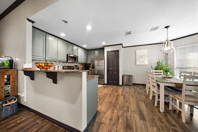 a kitchen with stainless steel appliances granite countertop a refrigerator a stove top oven a sink dishwasher and white cabinets with wooden floor