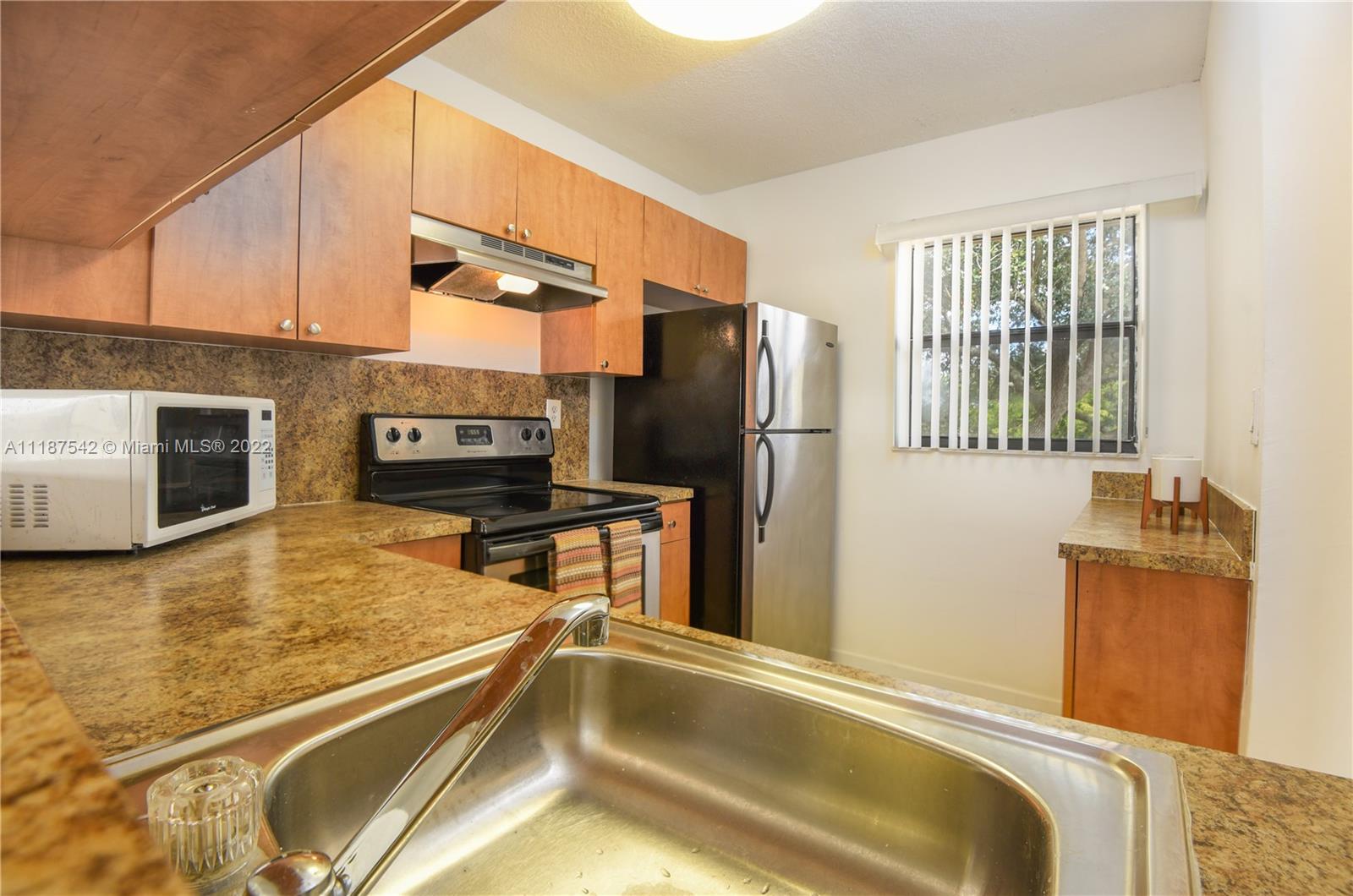 3199 Foxcroft Road, Unit 304 Miramar, FL 33025 - Photo 3 of 35 a kitchen with a refrigerator a stove and a sink with wooden floor