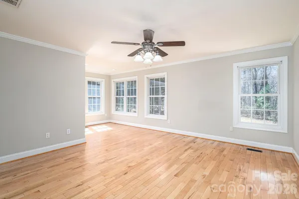 a view of an empty room with wooden floor and a window